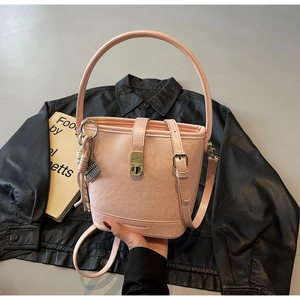 Sac seau rose texture lychee avec boucle dorée posé sur une veste en cuir noir