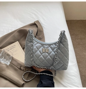 Detail of light blue quilted hobo bag with silver chain strap and metal swivel lock