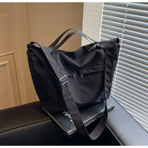Detail of black large capacity nylon tote with functional zipper pockets and sturdy straps