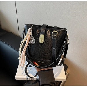 Détails du sac seau noir texturé craquelé avec fermoir doré et breloque de raquette