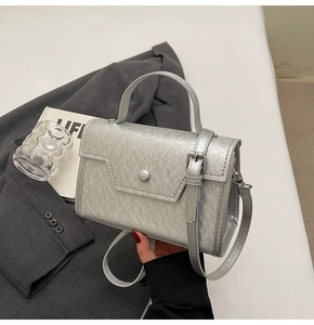 Silver metallic square handbag with round buckle shown in a stylish fashion scene setup
