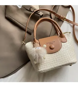 Détail du sac seau tissé beige avec rabat en cuir marron et breloque peluche