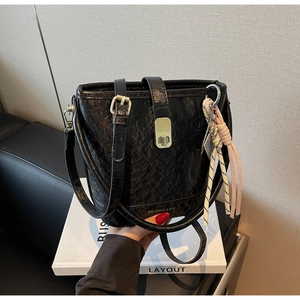 Détail du sac seau noir en cuir froissé avec fermoir doré et ornement en corde rayée