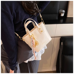 Detail of cream white tote bag with FASHION & YM print and gold tennis racket charm