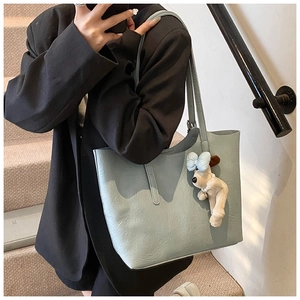 Detail of light blue tote bag with lychee texture and cute plush puppy charm