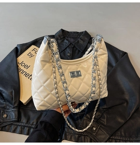Detailed view of white quilted hobo bag with silver chain and metal turn-lock closure