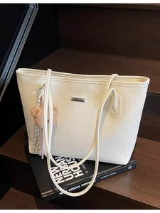 Borsa tote bianca a trama intrecciata con ciondolo a orsetto su scale in legno