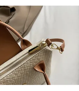Gros plan sur la fermeture dorée et la texture tissée du sac bandoulière beige