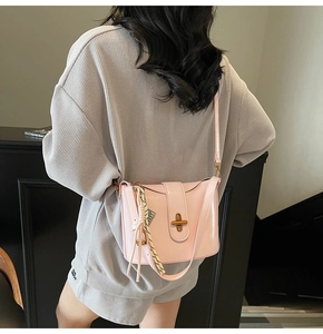 Detail of pink crossbody bucket bag with bronze twist lock and woven tassel accent