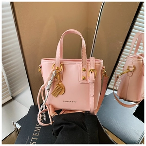 Detail of pink fashion handbag with golden charms and adjustable shoulder strap