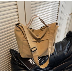 Detail of khaki nylon tote bag showing multi-zipper pockets and adjustable wide strap