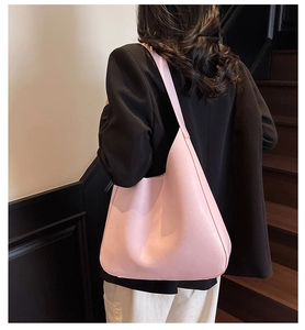 Grand sac fourre-tout rose chic porté avec un costume sur un escalier intérieur lumineux