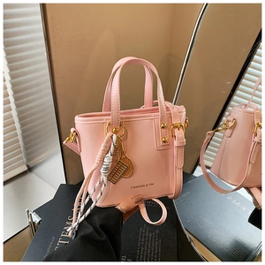 Detailed close-up of a pink mini tote bag with gold rivets and decorative sport pendants
