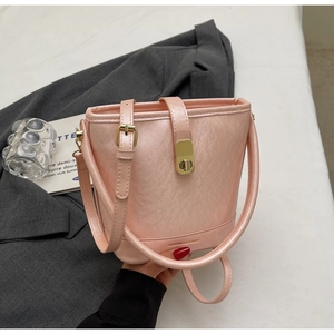 Détail du sac seau rose clair en cuir texturé avec fermoir doré et logo de la marque