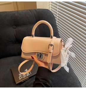 Detail of pink crossbody bag with silver rotating lock, lace ribbon and pearl charm