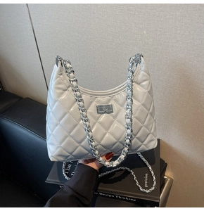 Detail of silver chain strap and metal lock on a quilted grey crossbody bag