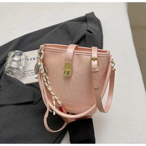 Détail d'un sac seau rose clair avec ferrures dorées et pendentif en corde tressée