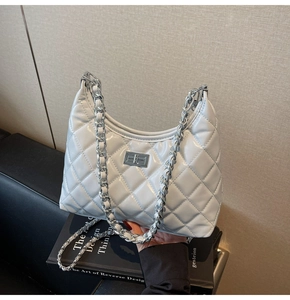 Close-up of white quilted leather bag with silver chain strap and metal swivel lock