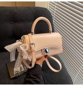 Detail of pink leather handbag featuring lace bow, pearl pendant and silver rotary lock
