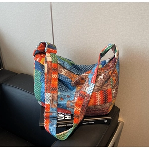 Detailed macro of vintage bohemian patchwork bag featuring wide strap and ethnic patterns