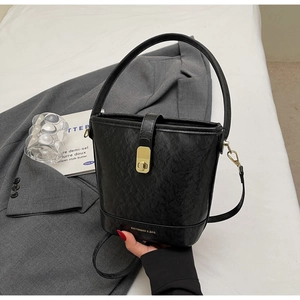 Détail d'un sac seau en cuir noir avec fermoir rotatif et bandoulière amovible