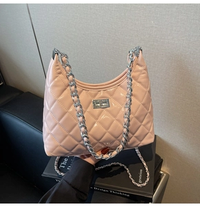 Detail of light pink quilted patent leather crossbody bag with silver chain and metal lock