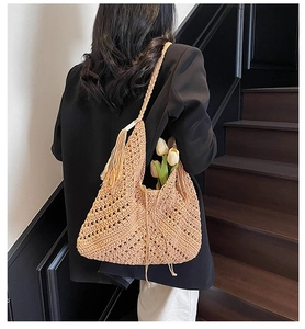 Detail of handmade crochet straw shoulder bag featuring geometric cutouts and chic tassels