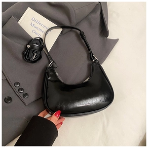 Detail of black leather crescent underarm bag with silver branding and dual straps