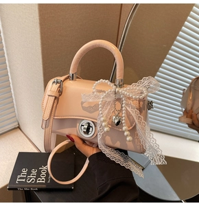 Close-up of pink crossbody bag featuring white lace bow and elegant pearl charm detail