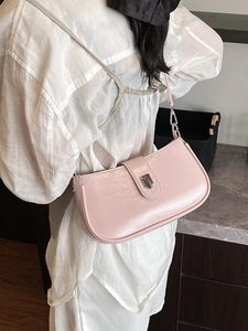 Pink patent leather baguette bag with silver buckle shown on shoulder for sizing