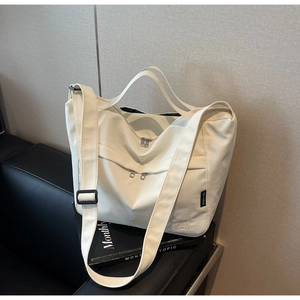 Detail of white nylon tote bag showing zipper closure, handle, and adjustable strap