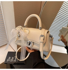 Detail of off-white crossbody bag with silver twist lock and pearl lace bow charm