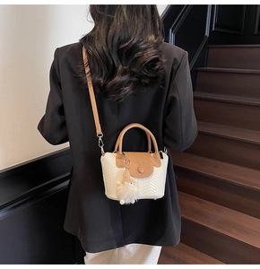 Détail du sac seau tissé avec rabat marron et accessoire de charme en peluche