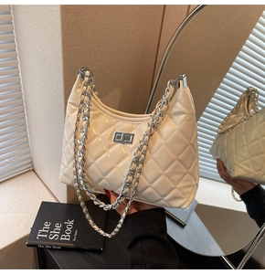 Detail of white quilted chain bag with silver twist lock and glossy leather finish