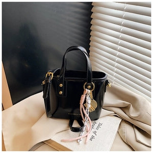 Detail of black patent leather bag with gold hardware and pink tassel accessory