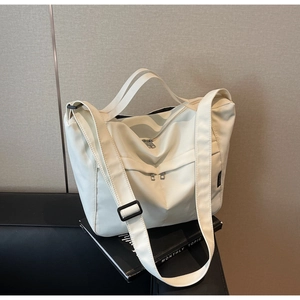 Detail of off-white tote bag with multiple zipper pockets and adjustable strap