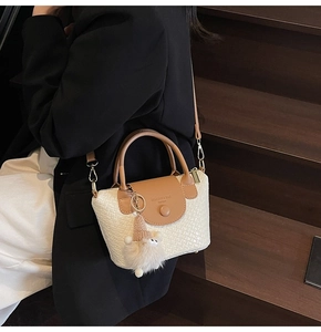Detail einer cremefarbenen Webhandtasche mit braunem Leder und Plüsch-Anhänger am Model