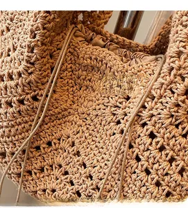 Close-up of handmade hollow crochet weave pattern and drawstring closure on khaki beach bag