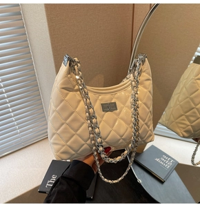 Close-up of white quilted patent leather hobo bag with silver chain and metal lock