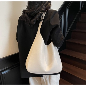 Vue détaillée d'un sac hobo minimaliste crème porté par un mannequin dans un bureau chic