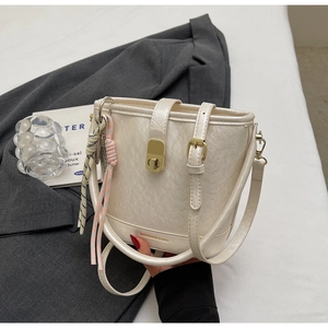Vue détaillée du sac seau crème avec fermoir tournant doré et charme tissé