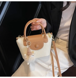 Detail der weißen gewebten Ledertasche mit braunem Griff und Monster-Anhänger