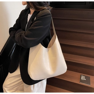 Vue détaillée d'un grand sac hobo crème porté à l'épaule pour un style minimaliste