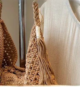 Close-up of handmade crochet straw tote bag showing fringe tassels and woven texture