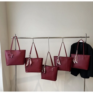 Detailansicht von fünf weinroten Shopper-Taschen aus mattem Leder mit goldenem Logo