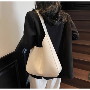 Sac hobo chic en cuir blanc crème porté à l'épaule dans un intérieur élégant