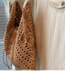 Detail of crochet straw beach bag with tassels and drawstring liner for women
