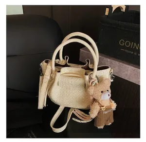 Détail du sac à main tissé crème avec un charm ours mignon et une bandoulière amovible