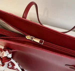 Detail of smooth gold zipper and red heart scarf on a luxury deep red tote bag