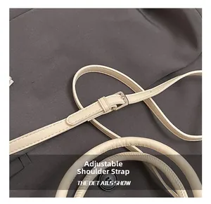 Gros plan sur la bandoulière réglable et les œillets en métal argenté du sac crème